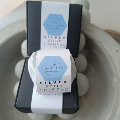 A  solid shampoo bar packaged and labeled as silver solid shampoo for blonde hair