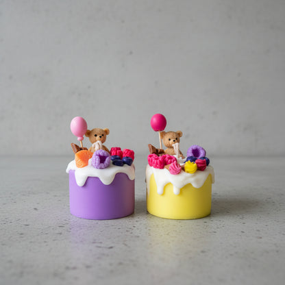 Two colorful cake candles with teddy bears and balloons on a plain background