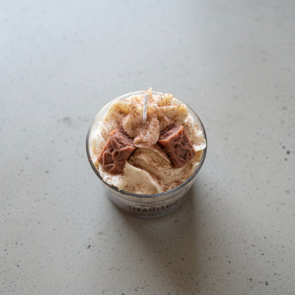 Tiramisu dessert in a glass container on a light surface