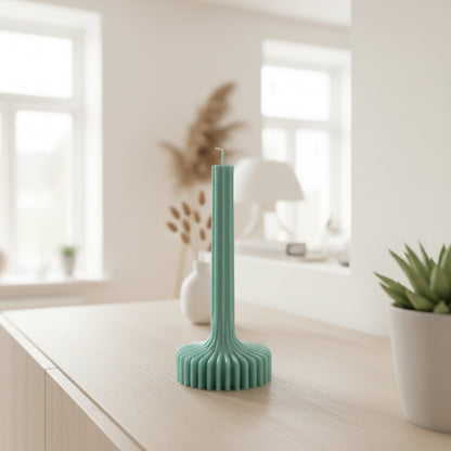 Green cactus-shaped candle on a beige surface with a light green background