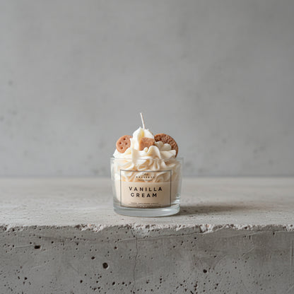 Κερί Vanilla Cream σε γυάλινο ποτήρι, τοποθετημένο σε επιφάνεια από ακατέργαστο τσιμέντο.