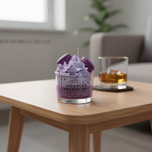 Purple candle labeled 'Purple Obsession' on a wooden table with a glass of whiskey in the background.