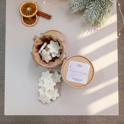 Snowflake-shaped soap bars with a container labeled 'Snowflake' on a light surface with decorative elements.