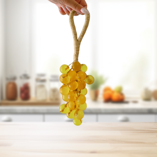 Hand holding a bunch of yellow soap grapes on a kitchen counter with a blurred background